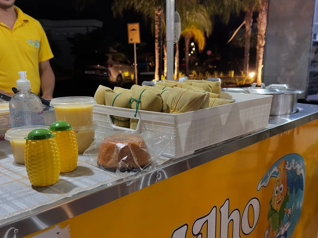 Balcão do carrinho Milho da Praia com pamonha, cural e bolo de milho servidos à noite