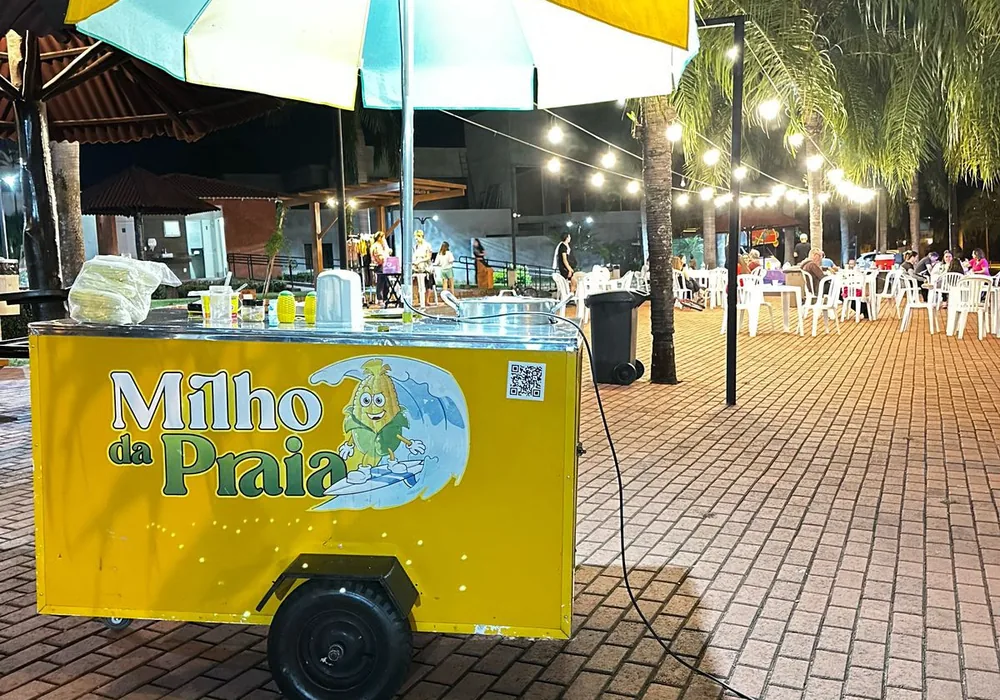 Carrinho do Milho da Praia com guarda-sol iluminado atendendo em evento à noite